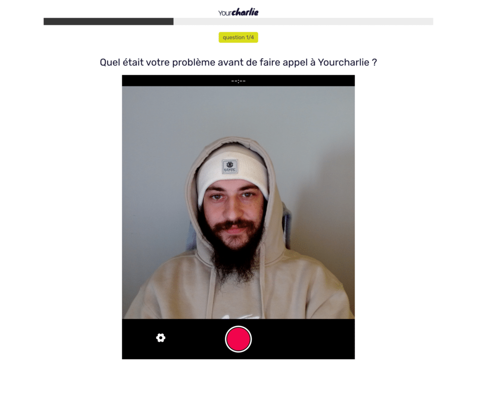Jeune homme en sweat à capuche participant à une session de témoignage vidéo sur YourCharlie avec la question 'Quel était votre problème avant de faire appel à Yourcharlie?' affichée à l'écran.